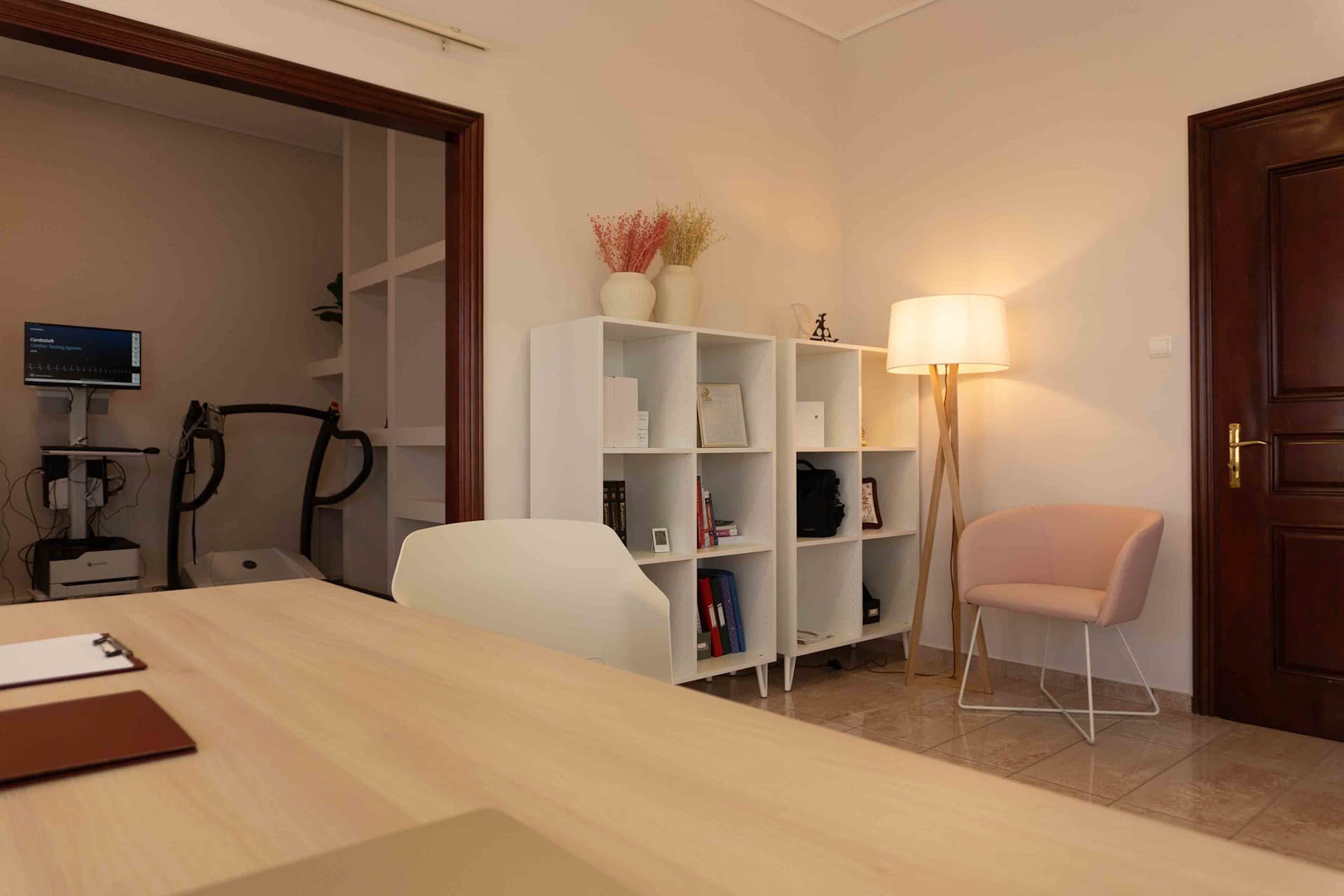 Γραφείο ιατρού με καρέκλα εξέτασης, υπολογιστή και ιατρικό εξοπλισμό σε καθαρό, οργανωμένο χώρο