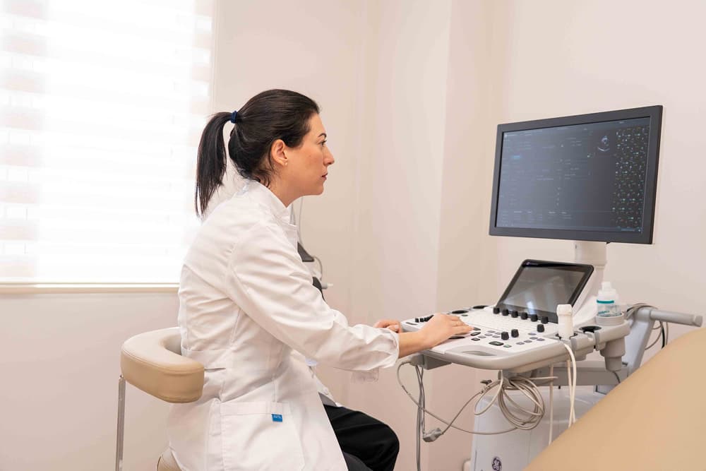 Η γιατρός καθισμένη χειρίζεται το μηχάνημα εξέτασης για υπέρηχο καρδιάς και αορτής